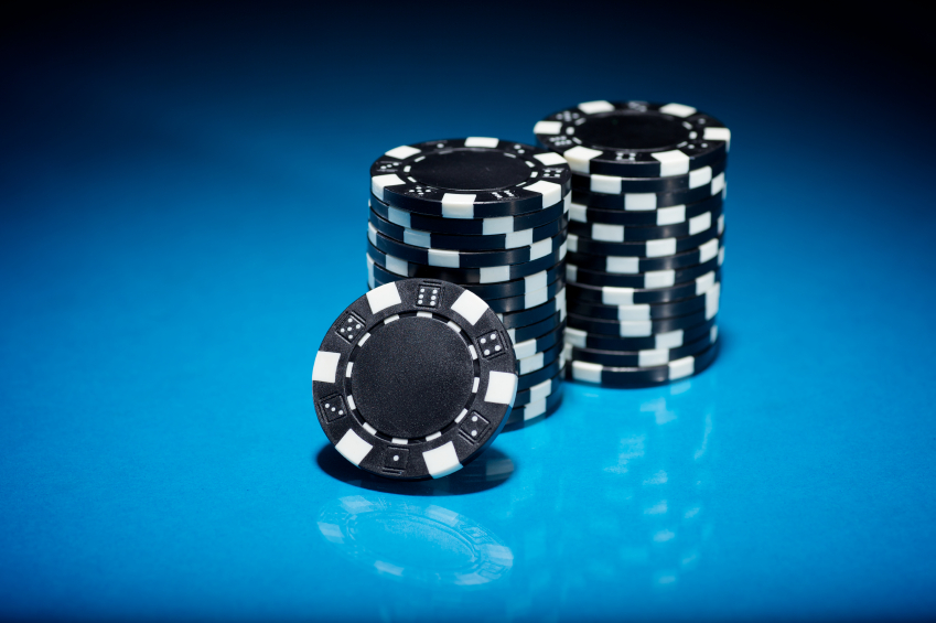 Black poker chips against a blue back ground